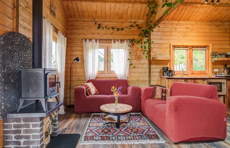 Gemuetliches Wohnzimmer des Ferienhauses in Callantsoog, Nordseekueste, Nordholland mit Holzofen und bunter Dekoration.