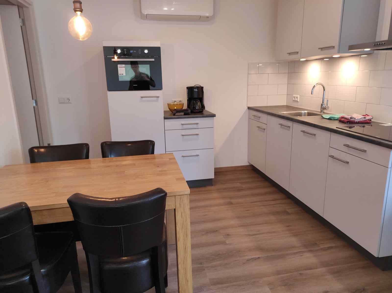 Gemuetliches Wohnzimmer des NH213 Ferienhauses in Callantsoog, Nordholland, mit bequemen Sofas und Essecke.