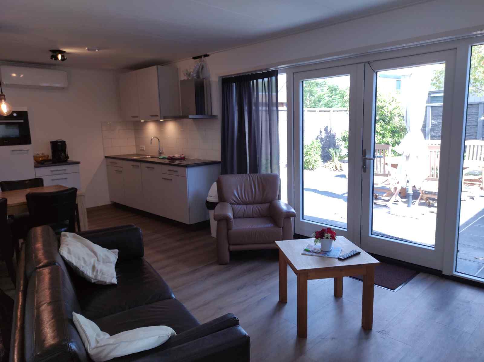 Aussenansicht des Ferienhauses NH213 in Callantsoog, Nordseekueste, mit roten Ziegeln und gruener Tuer.