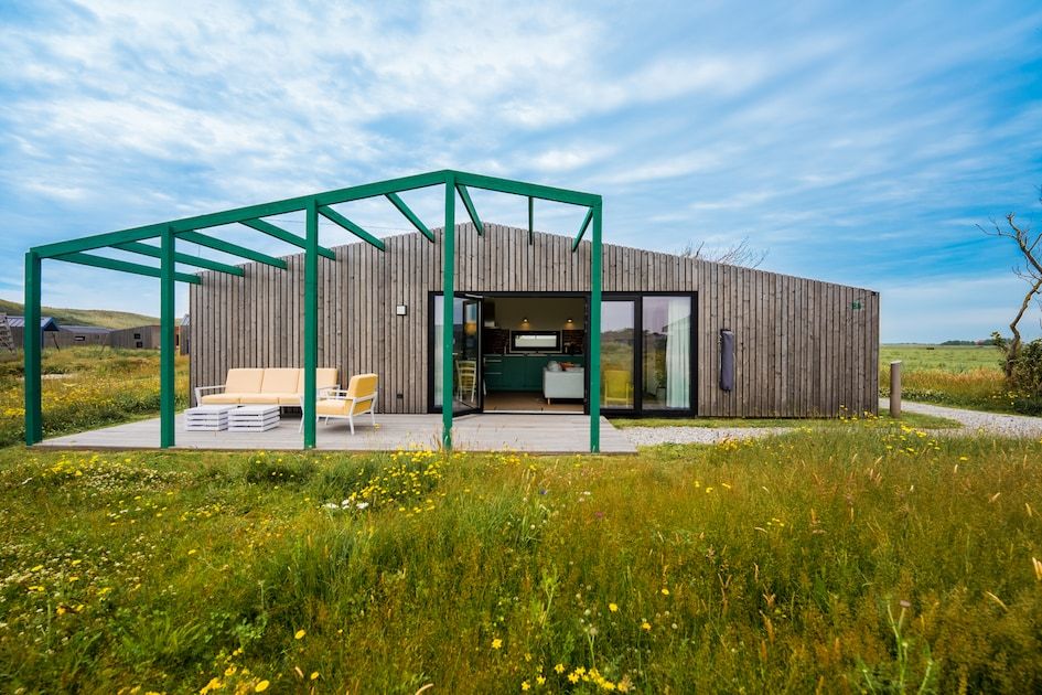 Aussenansicht des Ferienhauses Royal Dune 4 in Callantsoog mit grosser Veranda und natuerlicher Umgebung.