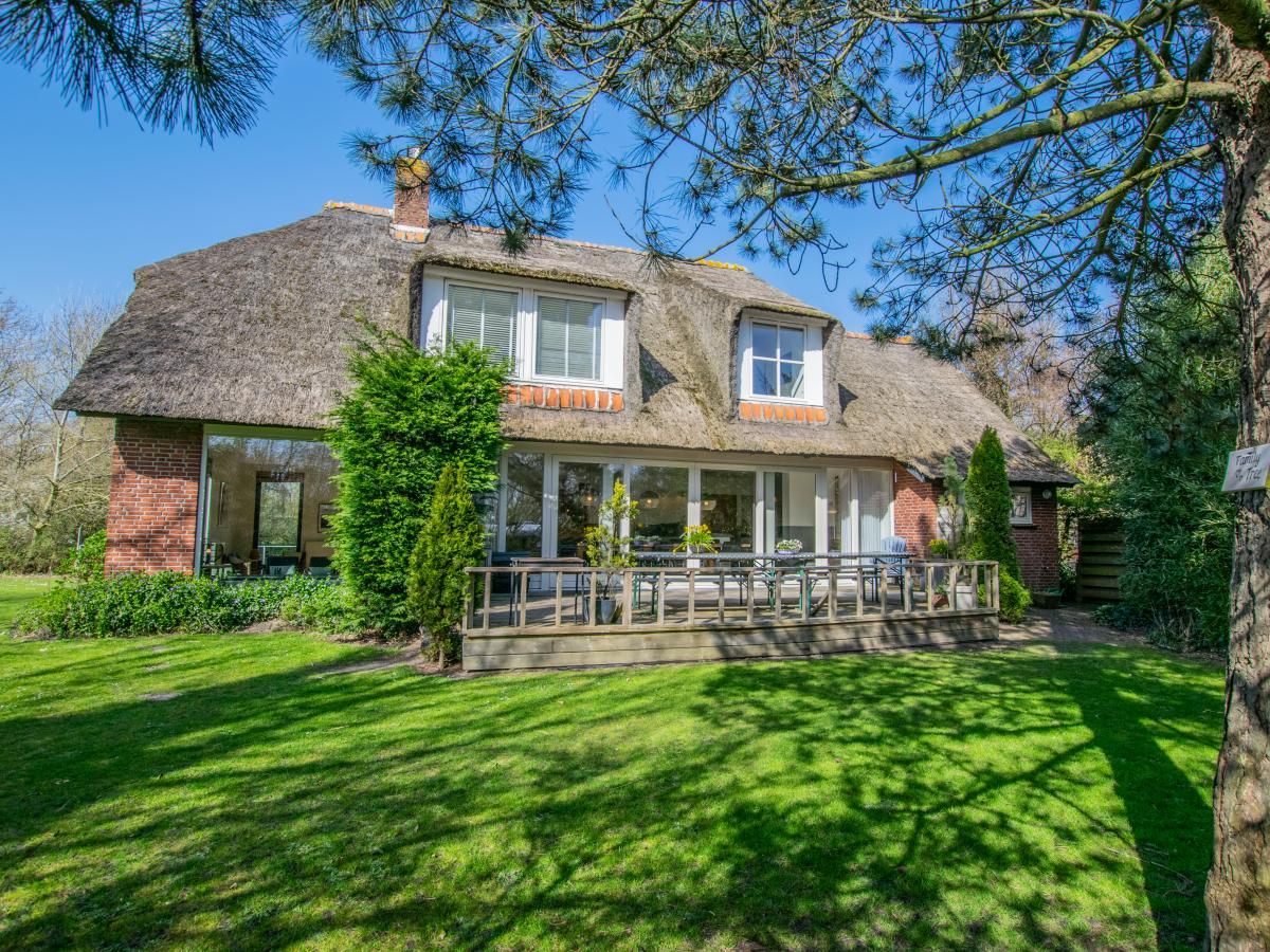 Landhuis Duinzicht in Callantsoog, een charmant vakantiehuis aan de Noordzeekust met rieten dak en zonnig terras te midden van groene natuur.
