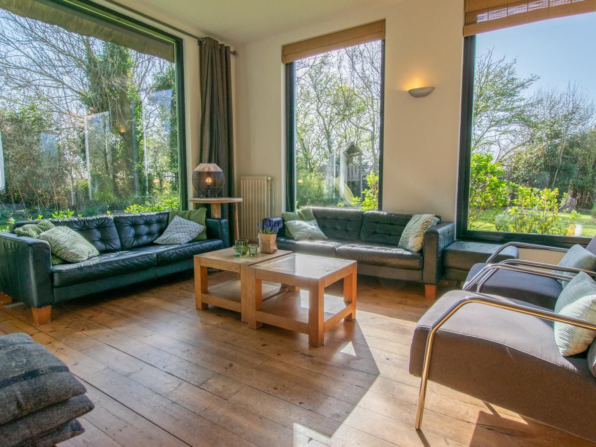 Gezellige woonkamer van Landhuis Duinzicht in Callantsoog, Noord-Holland met uitzicht op de groene tuin aan de Noordzeekust.