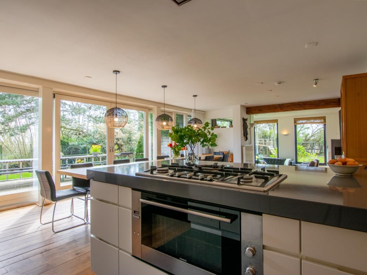 Ruime keuken met uitzicht op de tuin in Landhuis Duinzicht, een vakantiehuis in Callantsoog aan de Noordzeekust, Noord-Holland.