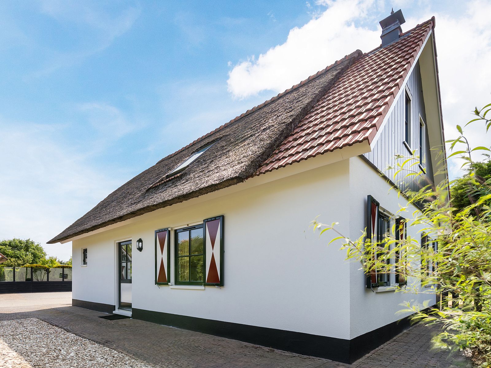 Freistehendes Haus in Callantsoog, Nordseekste, Nordholland, Ferienhaus mit Reetdach und stimmungsvoller Fassade unter blauem Himmel.