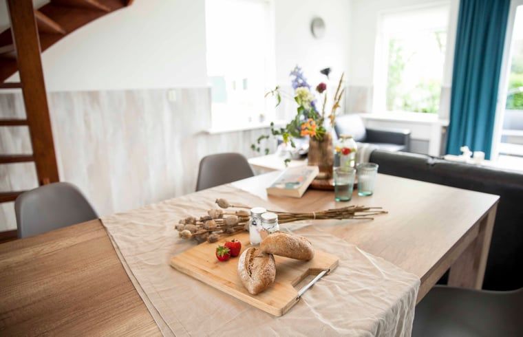 Esstisch im Ferienhaus in Callantsoog, Nordseekueste, Nordholland, mit frischem Brot und Blumen.
