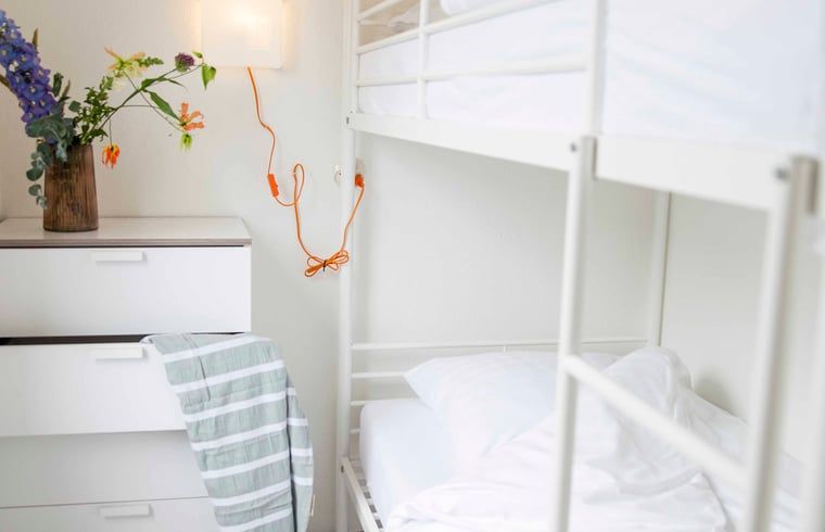 Schlafzimmer mit Etagenbett im Ferienhaus in Callantsoog, Nordseekueste, Nordholland, mit bunten Blumen.