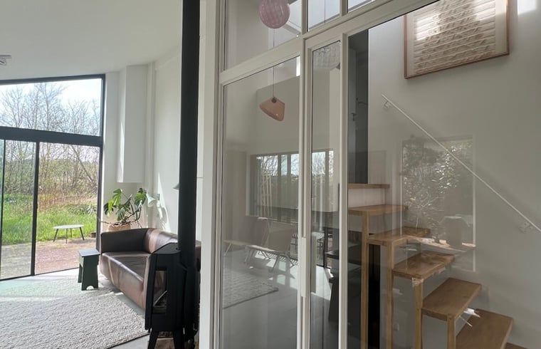 Helles Wohnzimmer des Huisje in Egmond-Binnen, Ferienhaus an der Nordseekueste in Nordholland, mit Blick auf die natuerliche Umgebung.