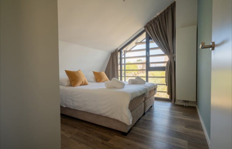 Lichte slaapkamer met grote ramen in Huisje in Egmond aan den Hoef, vakantiehuis aan de Noordzeekust.