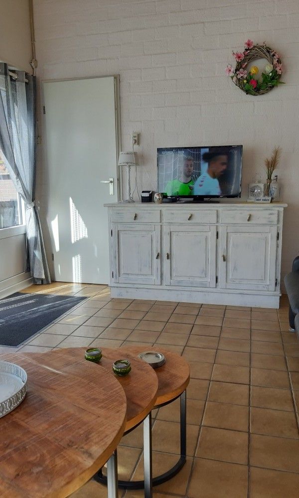Woonkamer van Rekere 111 vakantiehuis in Schoorldam, Noordzeekust, Noord-Holland met televisie en houten meubels.
