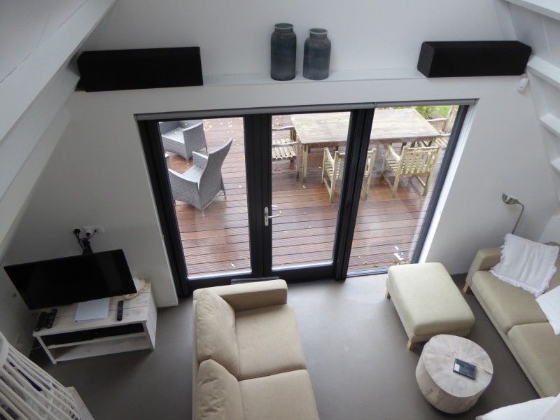 Lichte woonkamer met uitzicht op terras in Sandepark 29 vakantiehuis, Groote Keeten, Noordzeekust, Noord-Holland.