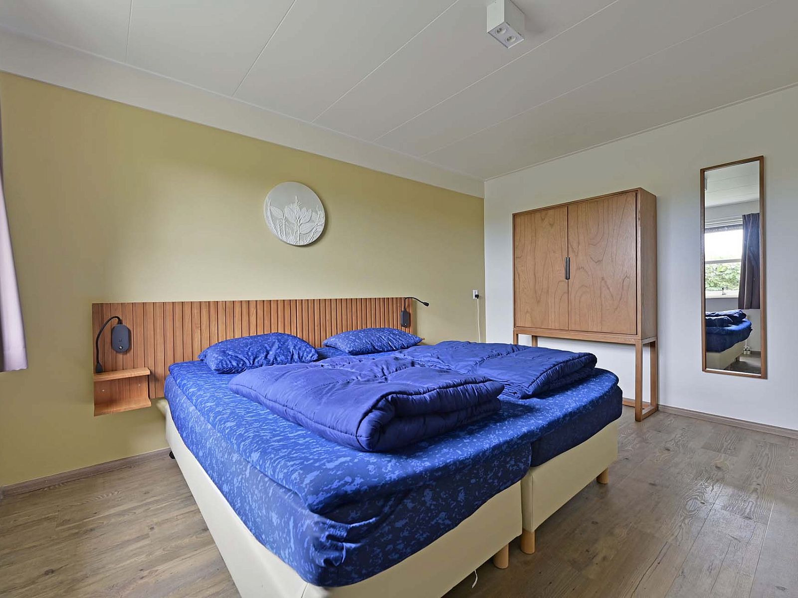 Comfortabele slaapkamer met houten kast in vakantiehuis Julianadorp aan Zee.