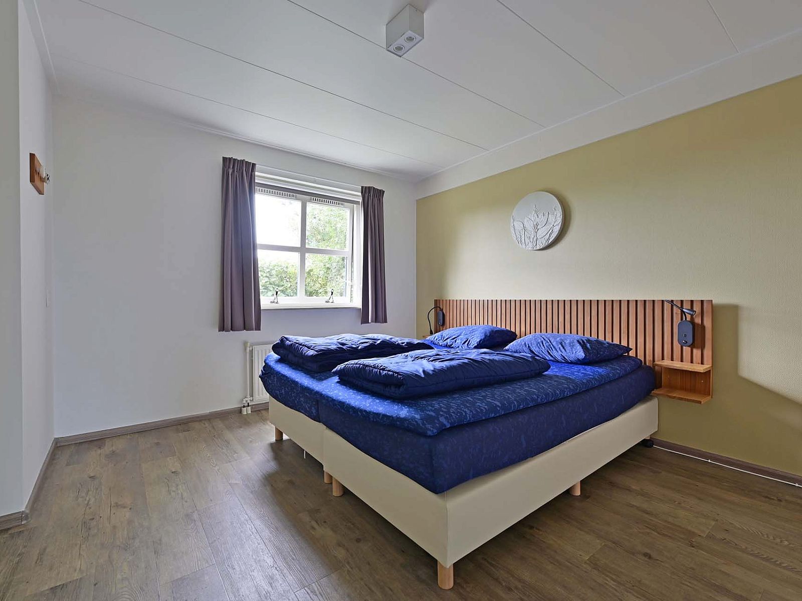 Lichte slaapkamer met uitzicht op tuin in vakantiewoning Julianadorp aan Zee.