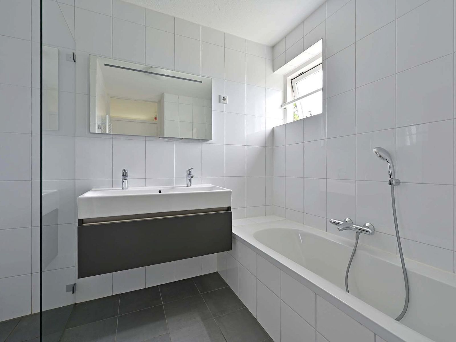 Badkamer met ligbad en dubbele wastafel in vakantiewoning Julianadorp aan Zee.