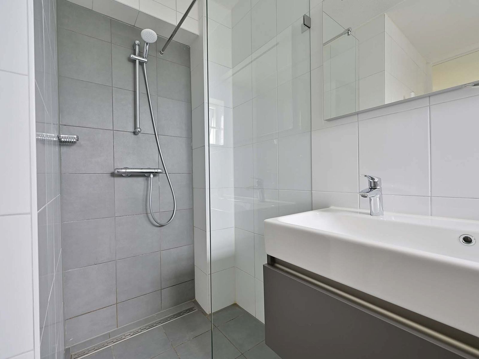 Inloopdouche met glazen wand in vakantiehuis Julianadorp aan Zee, Noord-Holland.