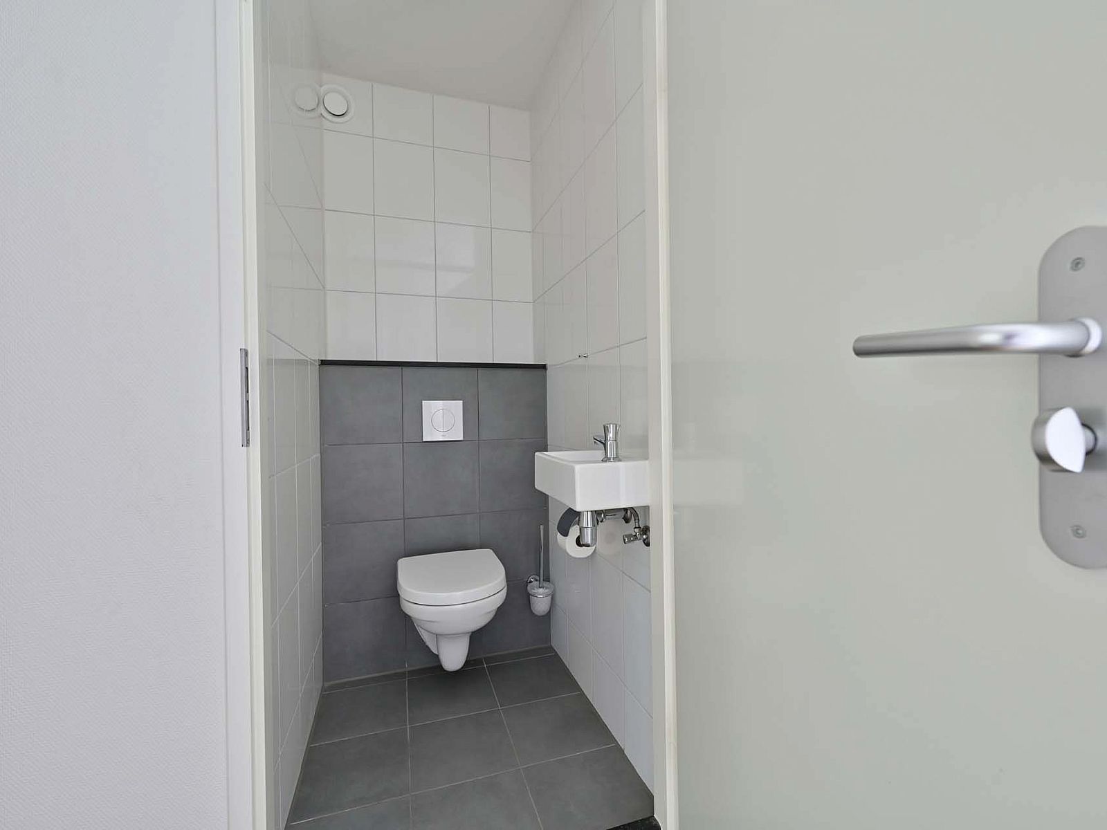 Modern toilet met witte tegels in vakantiewoning Julianadorp aan Zee.