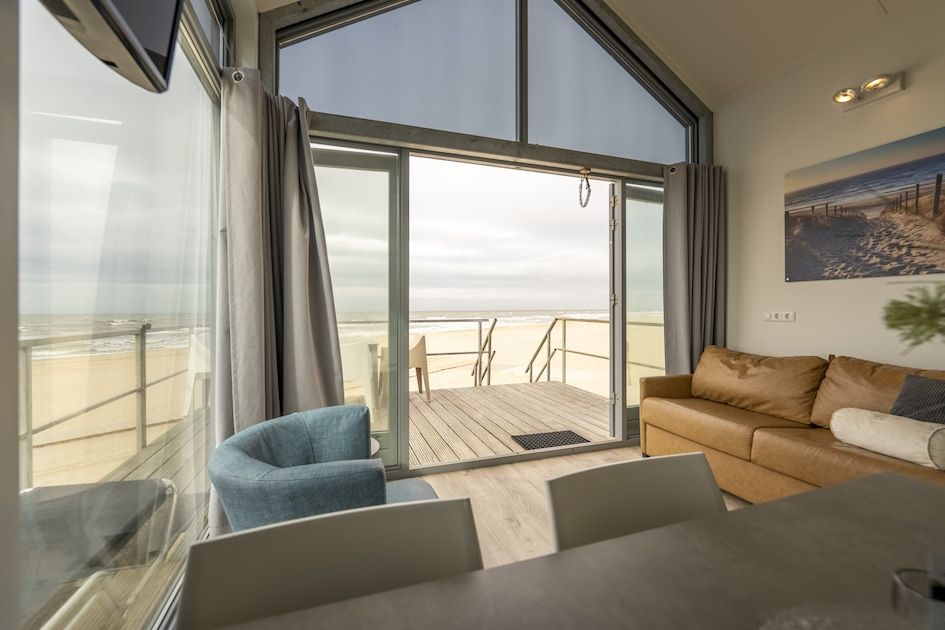 Geniet van het uitzicht op zee vanuit de lichte woonkamer van Beach House Comfort 4, een vakantiehuis in Julianadorp aan Zee, Noord-Holland.