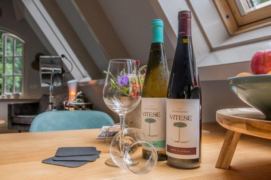 Gezellige eethoek in Casa Allegria, Bergen, met flessen wijn en glazen, ideaal voor een ontspannen avond aan de Noordzeekust.