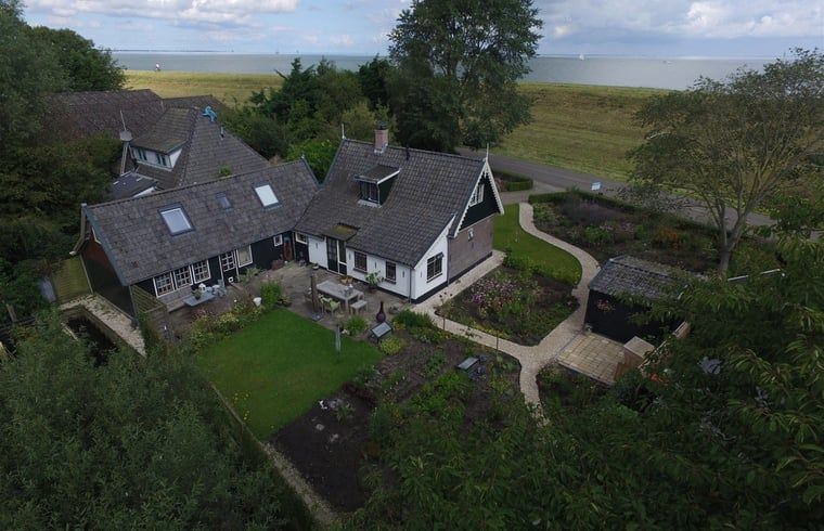 Luchtfoto van Vakantiehuis in Andijk aan de IJsselmeerkust, omringd door groen en uitzicht op het meer in Noord-Holland.