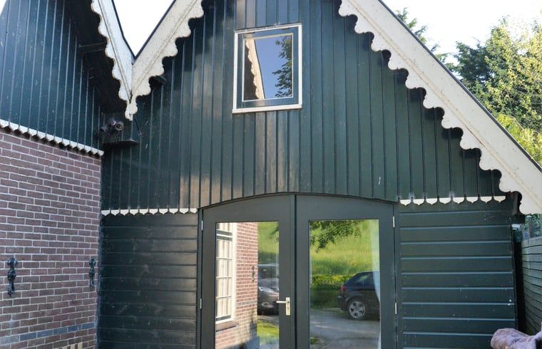 Charmante entree van Vakantiehuis in Andijk, met houten gevel in Noord-Holland, gelegen aan de serene IJsselmeerkust.