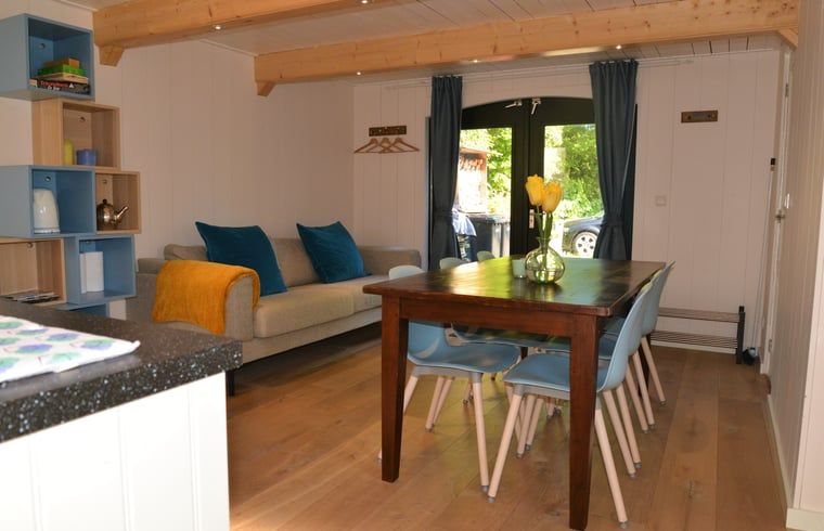 Stijlvolle woonkamer in Vakantiehuis in Andijk, met eettafel en comfortabele bank, gelegen aan de IJsselmeerkust in Noord-Holland.