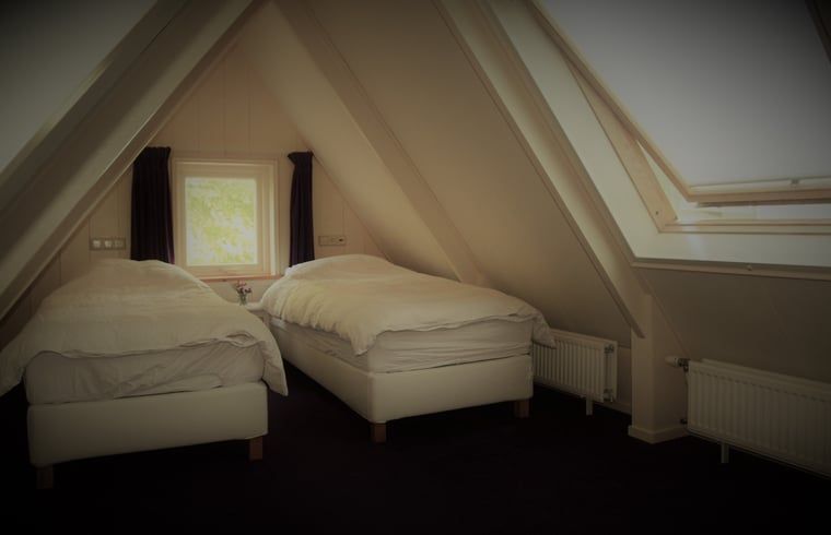 Ruime zolderkamer met dakraam in Vakantiehuis in Andijk, biedt comfortabele slaapruimte aan de IJsselmeerkust in Noord-Holland.