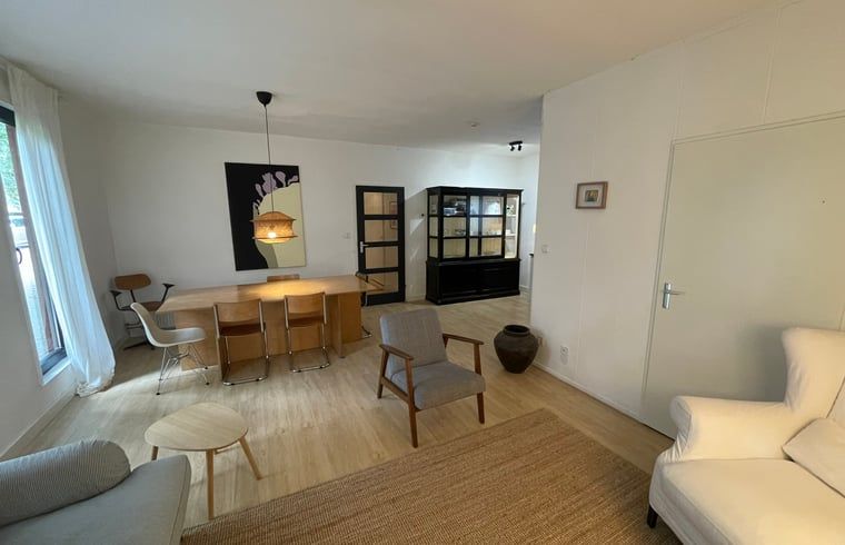 Geraeumiges Wohnzimmer des Ferienhauses in Andijk, IJsselmeerkueste, Nordholland mit bequemer Sitz- und Essecke.