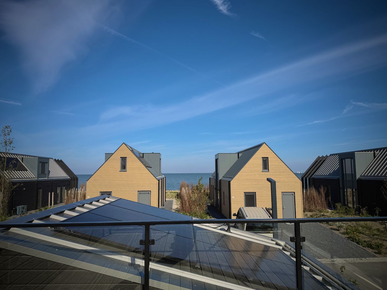 View from the detached house in Enkhuizen, overlooking the IJsselmeer and modern vacation homes in North Holland.