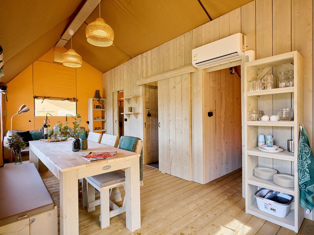 Comfortabele zithoek op het terras van safaritent 6-8ST in Huizen, omgeven door groen.