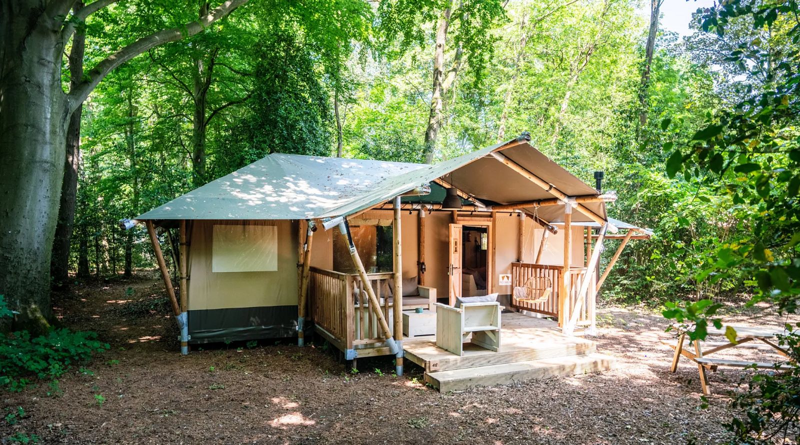 The Stille Heide tent house in Huizen, North Holland, offers a rustic glamping experience with a veranda and surrounding nature on the IJsselmeer coast.