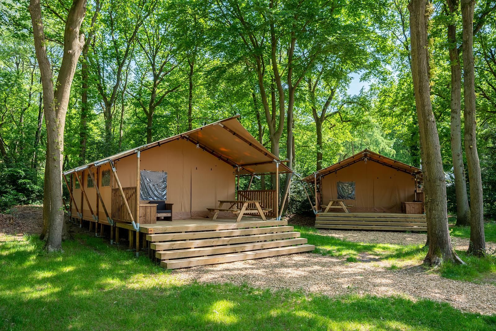 De Bos Escape glamping lodge in Huizen, Noord-Holland, omgeven door groene natuur en voorzien van een ruime veranda voor een ontspannen verblijf.