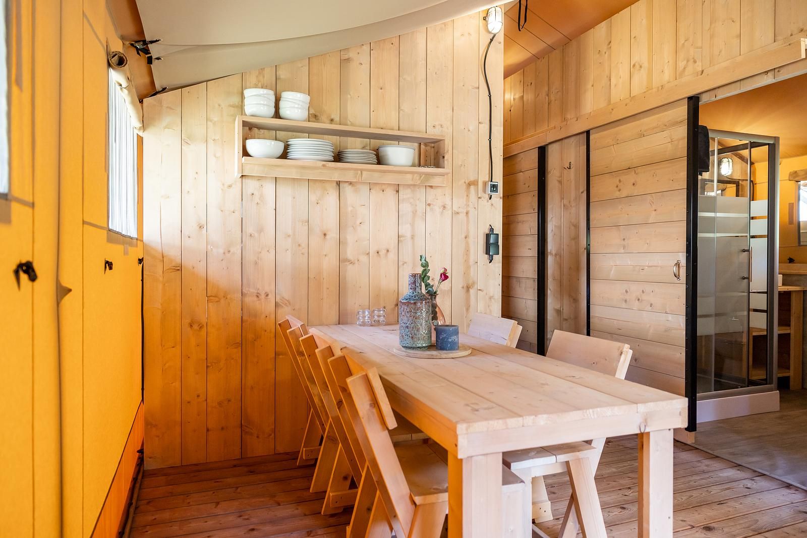 Gezellige eetruimte in De Bos Escape tenthuis, Huizen, met houten interieur en eettafel, ideaal voor ontspannen vakantie aan de IJsselmeerkust.