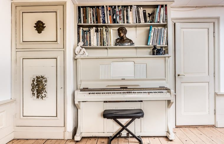 Piano en boekenplank in Vakantiehuis in Edam, culturele charme in Noord-Holland.