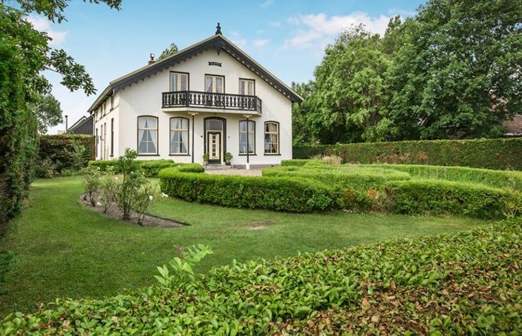 Stattliche Fassade von Cottage in Anna Paulowna, Ferienhaus in Nordholland, umgeben von einem ueppigen Garten.