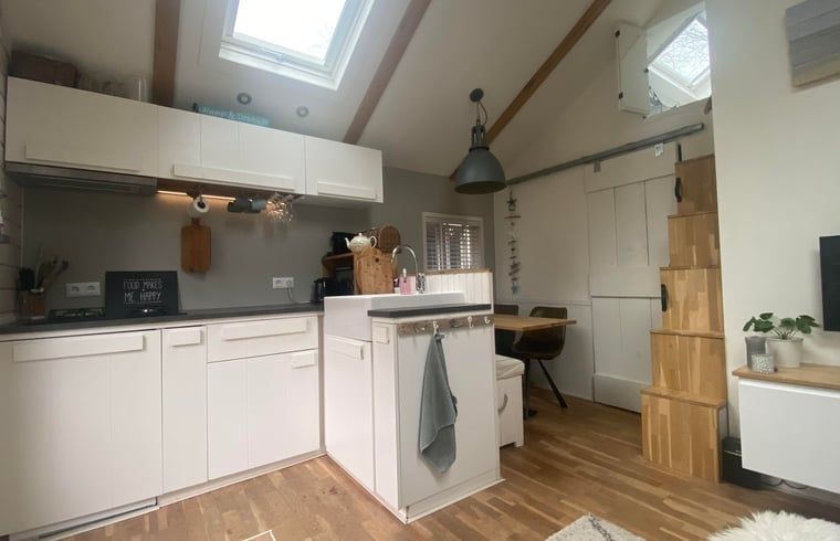 Cozy kitchen of Huisje in Schoorl, vacation home in North Holland, with modern furnishings and wooden details for a cozy atmosphere.