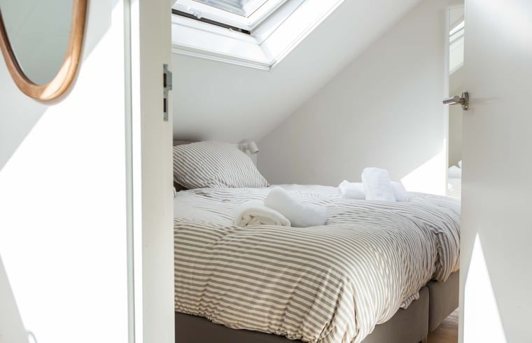 Lichte slaapkamer met dakraam in vakantiehuis Huisje in Schoorl, Noord-Holland noord.