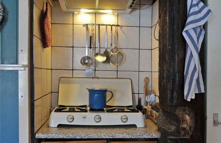 Cozy kitchen in vacation home in Schoorl, North Holland, with vintage stove and cookware, ideal for culinary adventures.