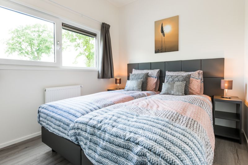 Gemuetliches Schlafzimmer im Modul 5-Personen-Ferienhaus, Berkhout, Nordholland, mit bequemen Betten und beruhigendem Blick auf die Natur.