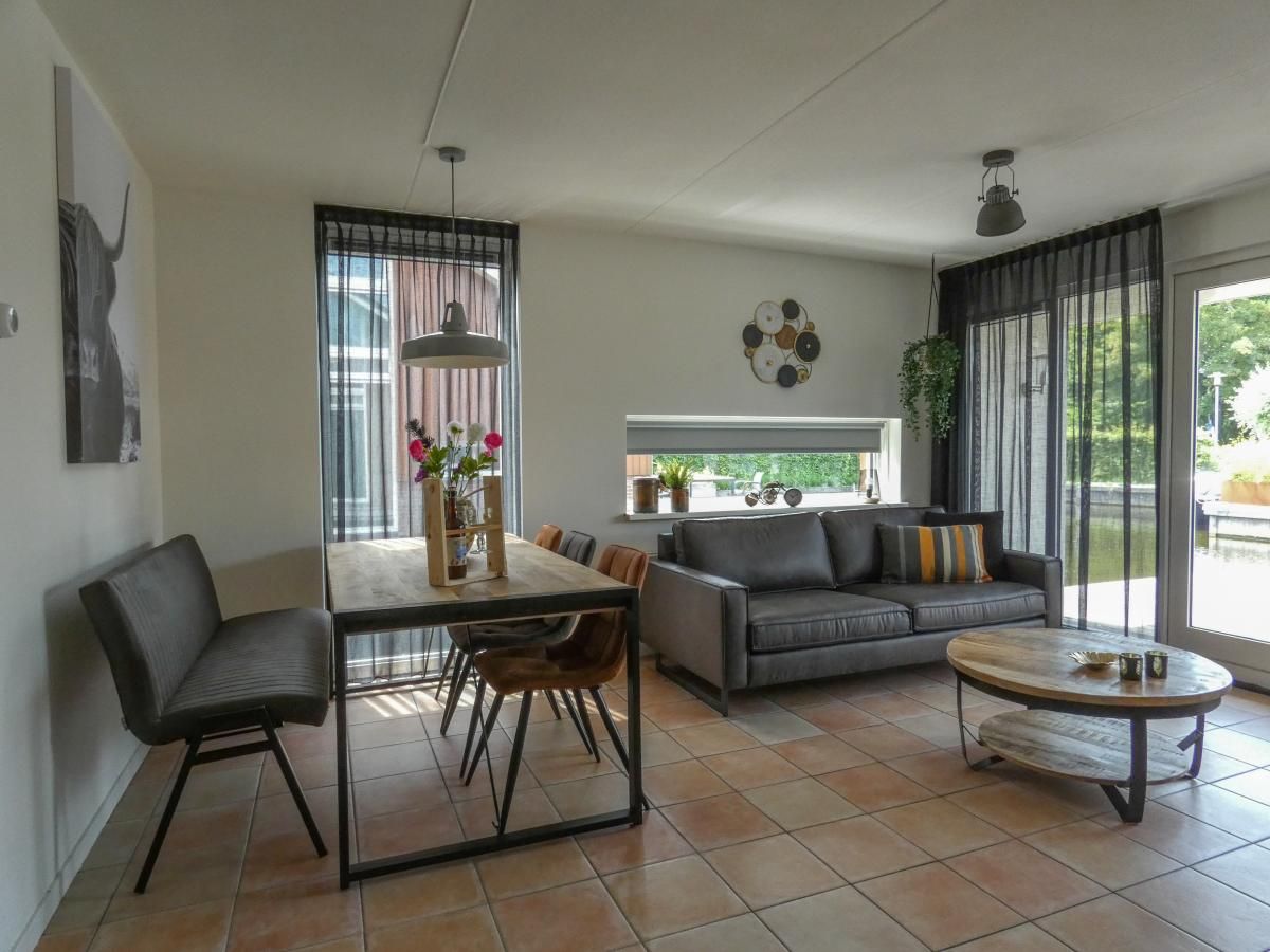 Gemuetliches Wohnzimmer des Ferienhauses Busch en Dam in Uitgeest, Nordholland, mit moderner Einrichtung und Blick auf den Garten.