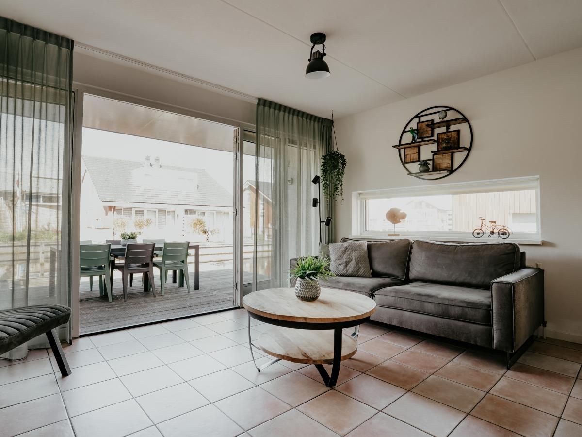 Gemuetliches Wohnzimmer des Ferienhauses Busch en Dam in Uitgeest, Nordholland, mit Blick auf die Terrasse und moderner Einrichtung.