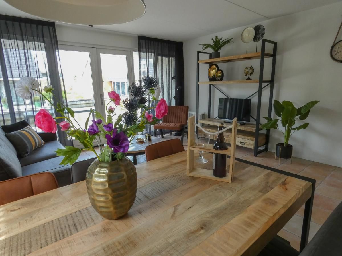 Gemuetliches Wohnzimmer im Ferienhaus Busch en Dam in Uitgeest, Nordholland, mit moderner Einrichtung und Blick auf den Garten.