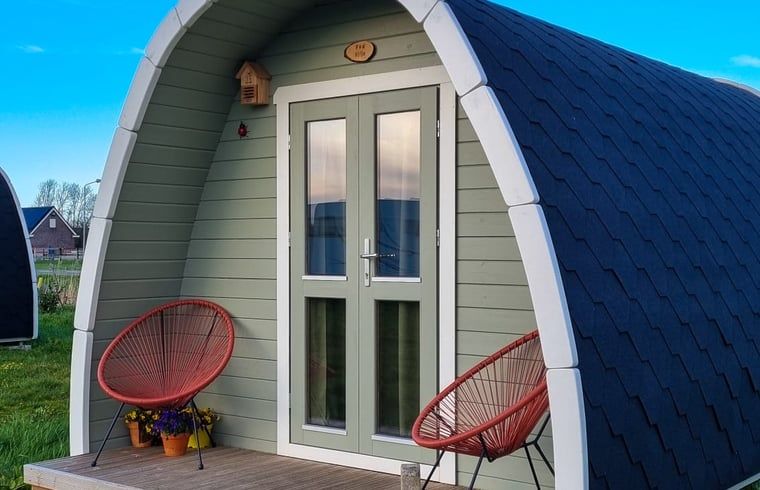 Gezellige veranda van Huisje in Zuid-Scharwoude, een vakantiehuis in Noord-Holland, met uitzicht op de groene omgeving.