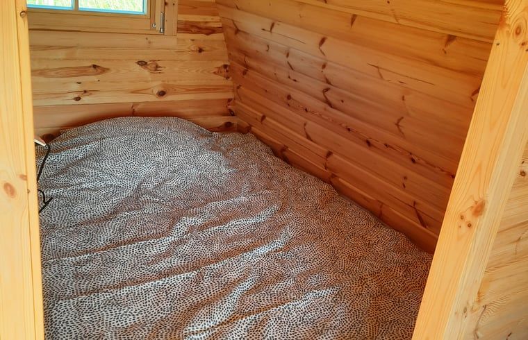 Knusse slaapkamer in Huisje in Zuid-Scharwoude, een vakantiehuis in Noord-Holland, met houten wanden en comfortabel bed.