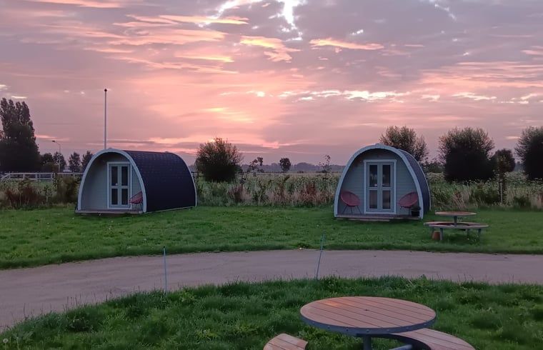 Twee vakantiehuisjes bij zonsondergang in Huisje in Zuid-Scharwoude, Noord-Holland, omgeven door een serene omgeving.