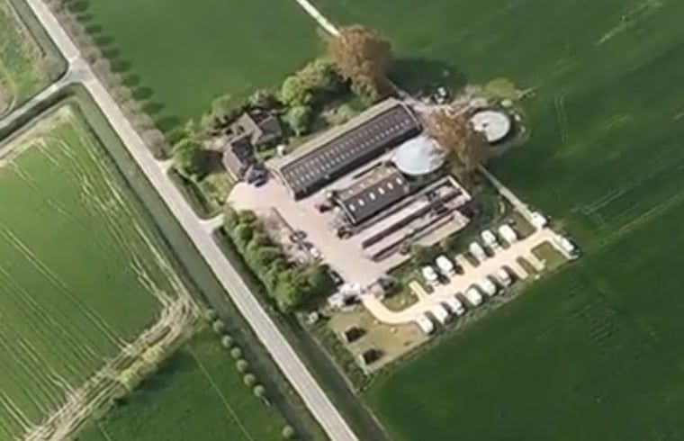 Dronefoto van de locatie van Huisje in Zuid-Scharwoude, een vakantiehuis in Noord-Holland, met uitgestrekte groene velden.