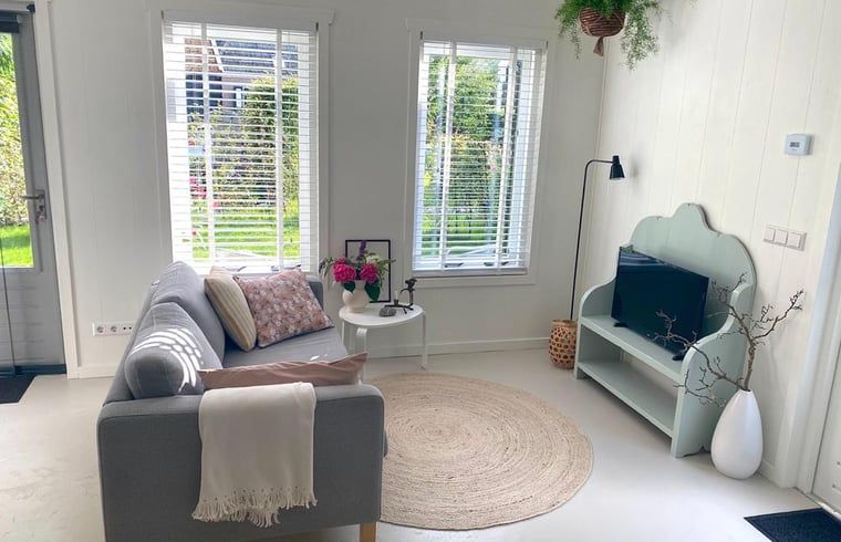 Cozy living room in Holiday Home in Driehuizen, North Holland, with comfortable sofa and garden view.