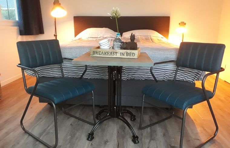 Gemuetliches Schlafzimmer in einem Ferienhaus in Nieuw Vennep, Nordholland, mit komfortabler Sitzecke und Fruehstuecksservice.