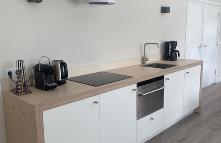 Moderne Kueche in einem Ferienhaus in Mander, Twente, Overijssel, mit schlichten weissen Schraenken und modernen Geraeten.