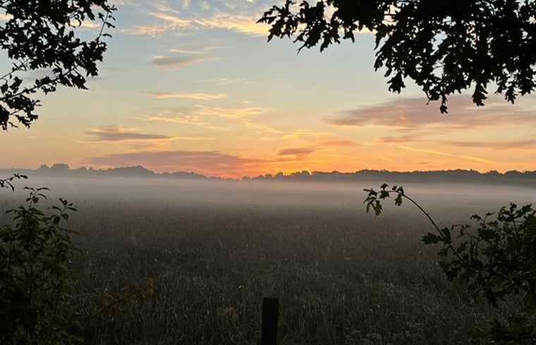 Atemberaubender Sonnenuntergang in der Naehe eines Ferienhauses in Mander, Twente, Overijssel, mit nebligen Feldern.