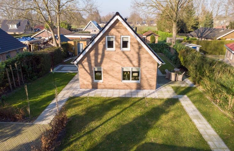 Buitenkant van Vakantiehuisje in Den Ham, Twente, omringd door groene tuin en charmante paden.
