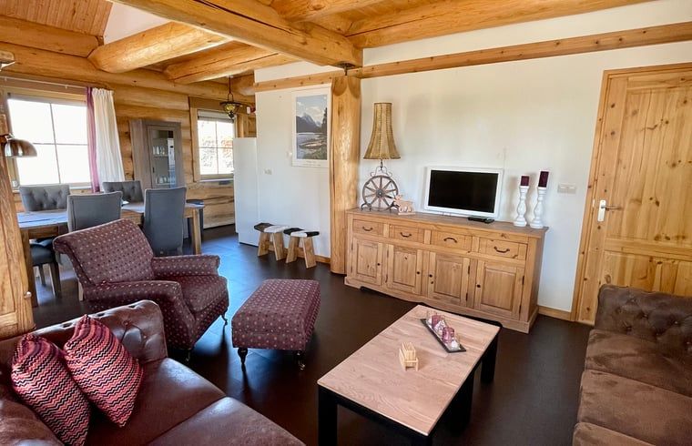 Gemuetliches Wohnzimmer im Ferienhaus in Den Ham, Twente, Overijssel. Inneneinrichtung aus Holz mit bequemen Sitzgelegenheiten und rustikalem Charme.